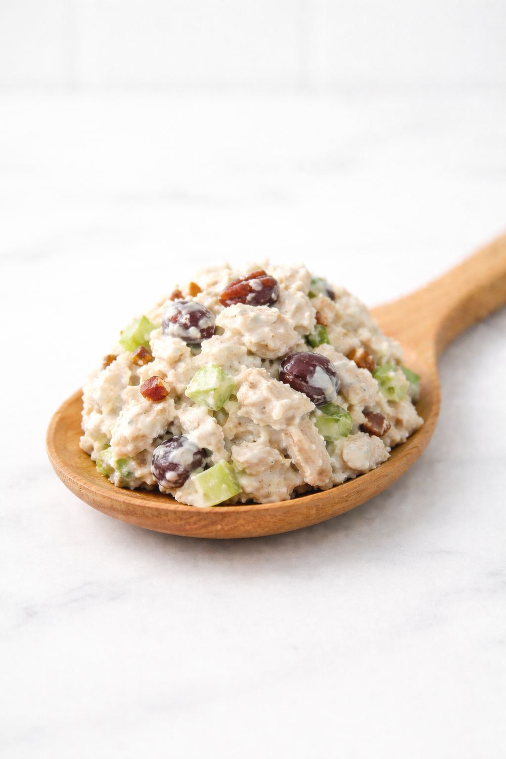 Bart's chicken salad with grapes and toasted pecans on a wooden spoon
